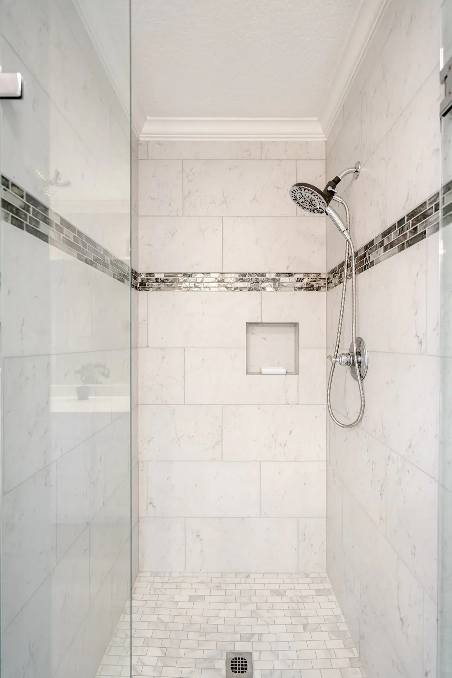 A walk in shower with a glass door and a shower head.