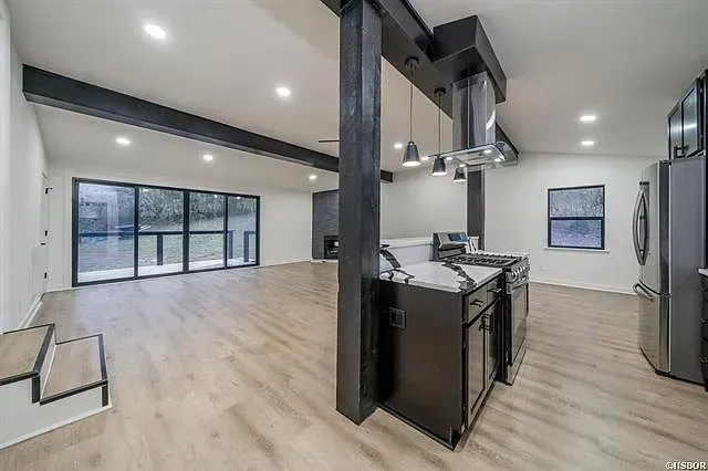 A large empty room with a kitchen , dining room , and living room.