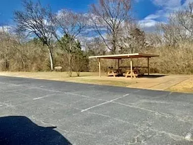 There is a picnic table under a shelter in the middle of a parking lot.