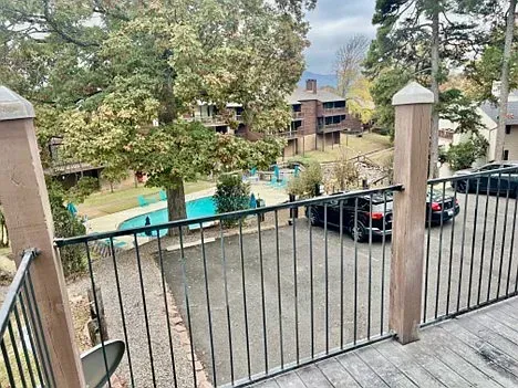 A balcony with a view of a swimming pool and a parking lot.