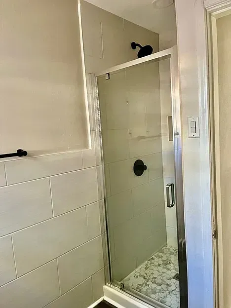 A bathroom with a sliding glass shower door and a black shower head.