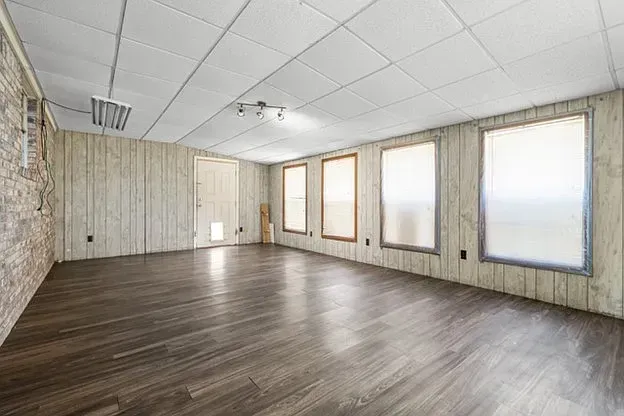 A large empty room with hardwood floors and a white ceiling.