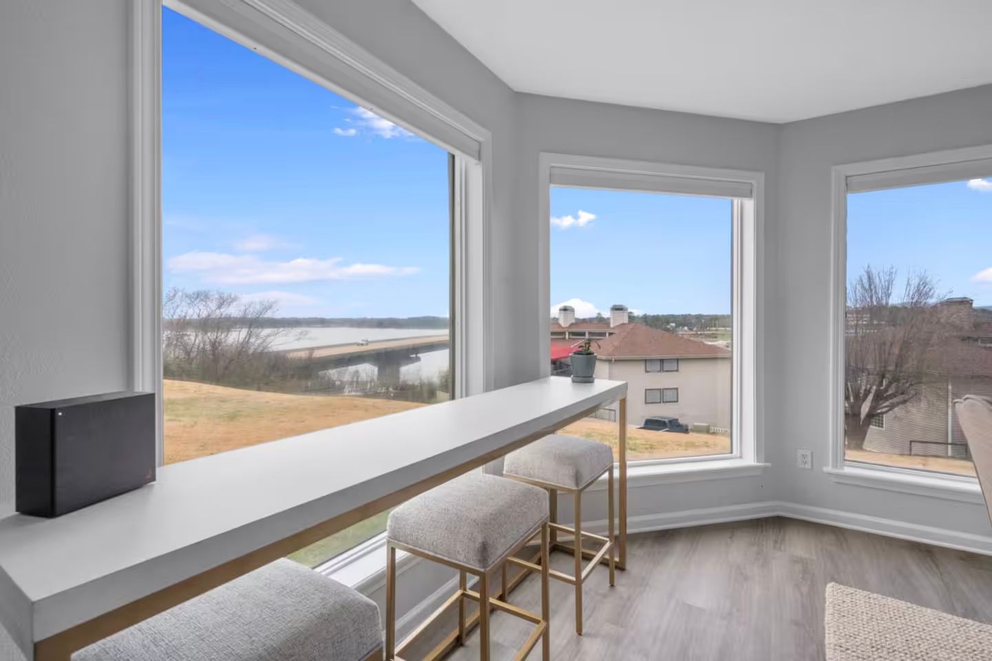 A living room with a table and stools and a large window.