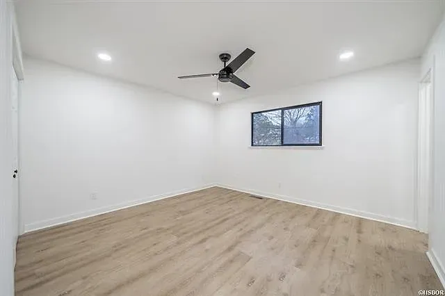 An empty bedroom with hardwood floors and a ceiling fan.