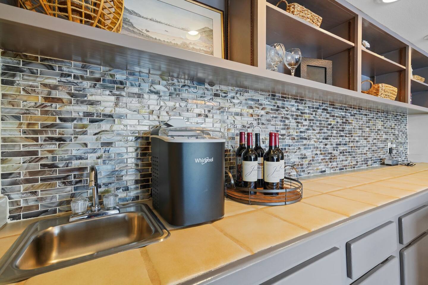 A kitchen with a sink and bottles of wine on the counter.