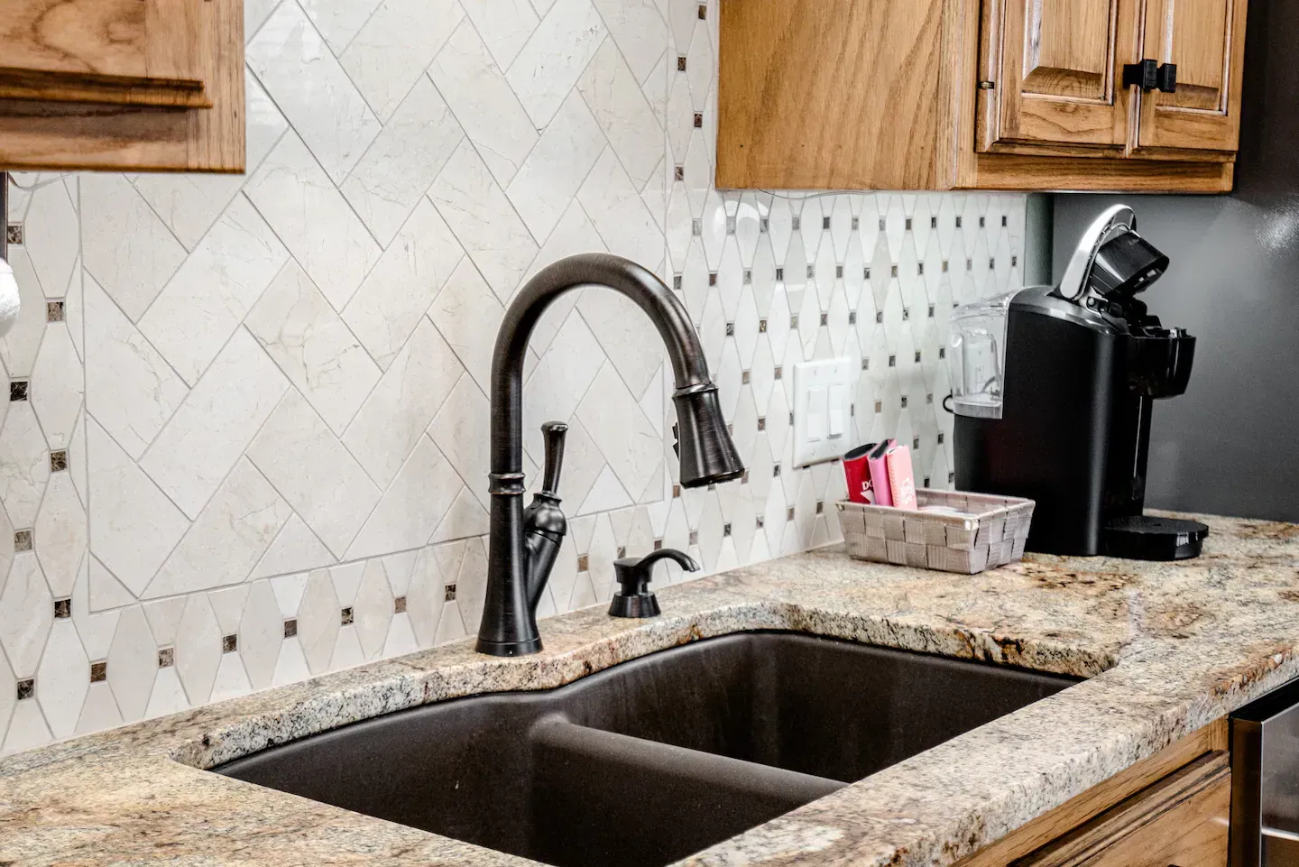 A kitchen sink with a faucet and a coffee maker on the counter.