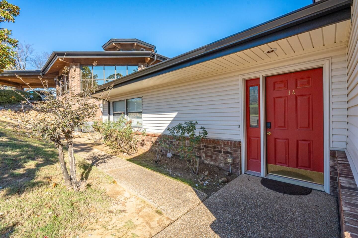 The front door of a house with a red door and a walkway leading to it.