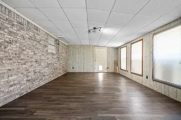 An empty room with hardwood floors and a brick wall.