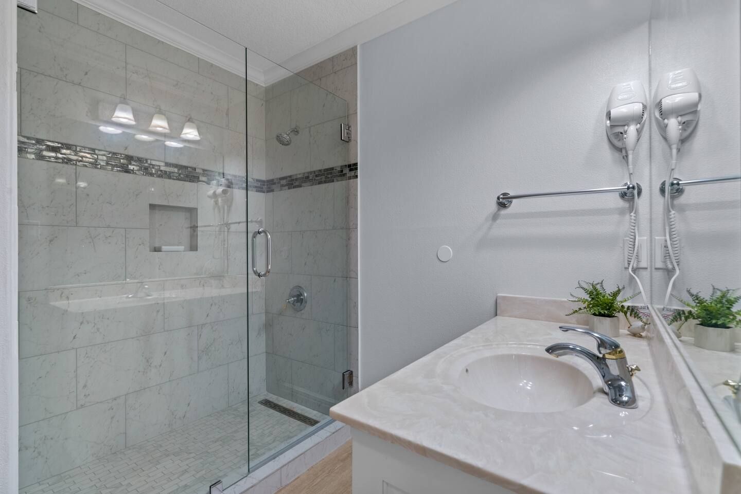 A bathroom with a sink , shower , and mirror.
