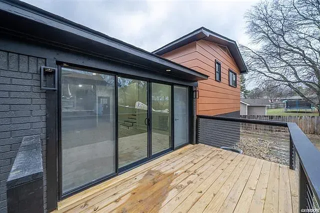 A wooden deck with sliding glass doors on the side of a house.