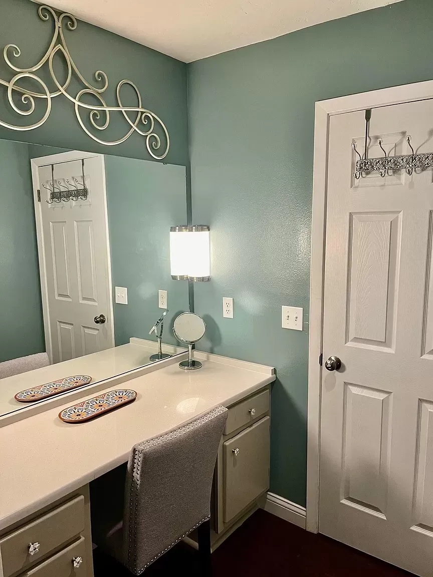 A bathroom with a vanity , mirror and chair.