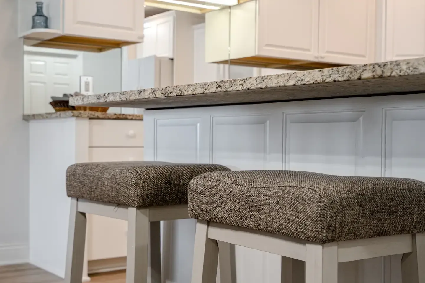 A kitchen with two bar stools and a granite counter top.
