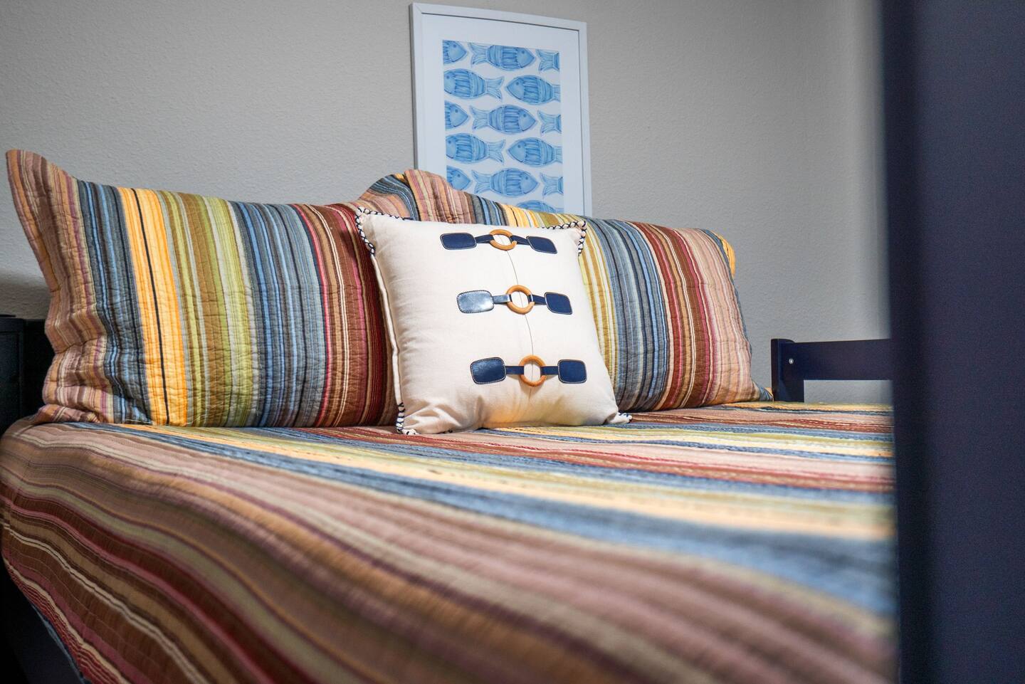 A bed with a striped comforter and pillows in a bedroom.