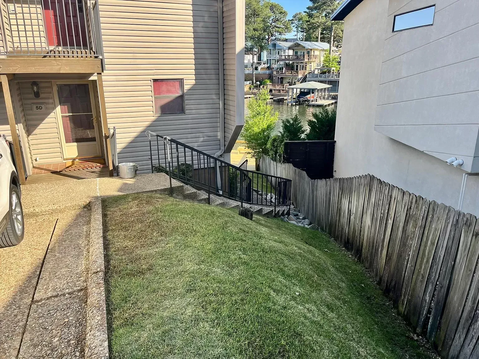 A car is parked in front of a house with stairs leading up to it.