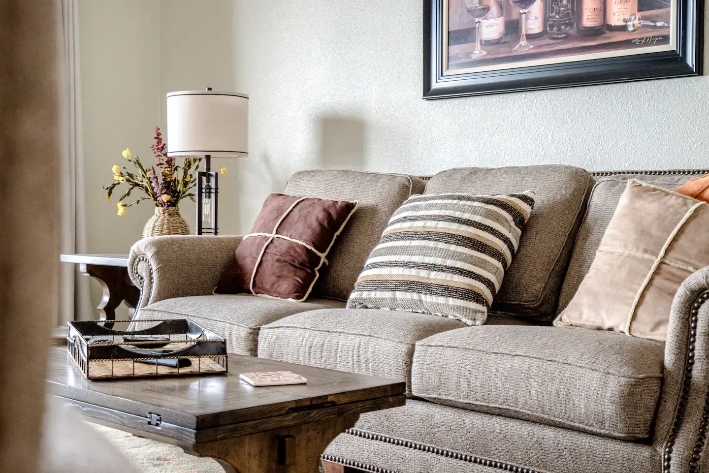 A living room with a couch , chair , table and lamp.