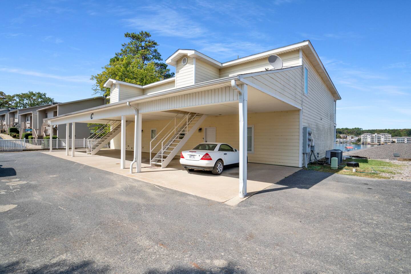 A white car is parked under a canopy in front of a building.