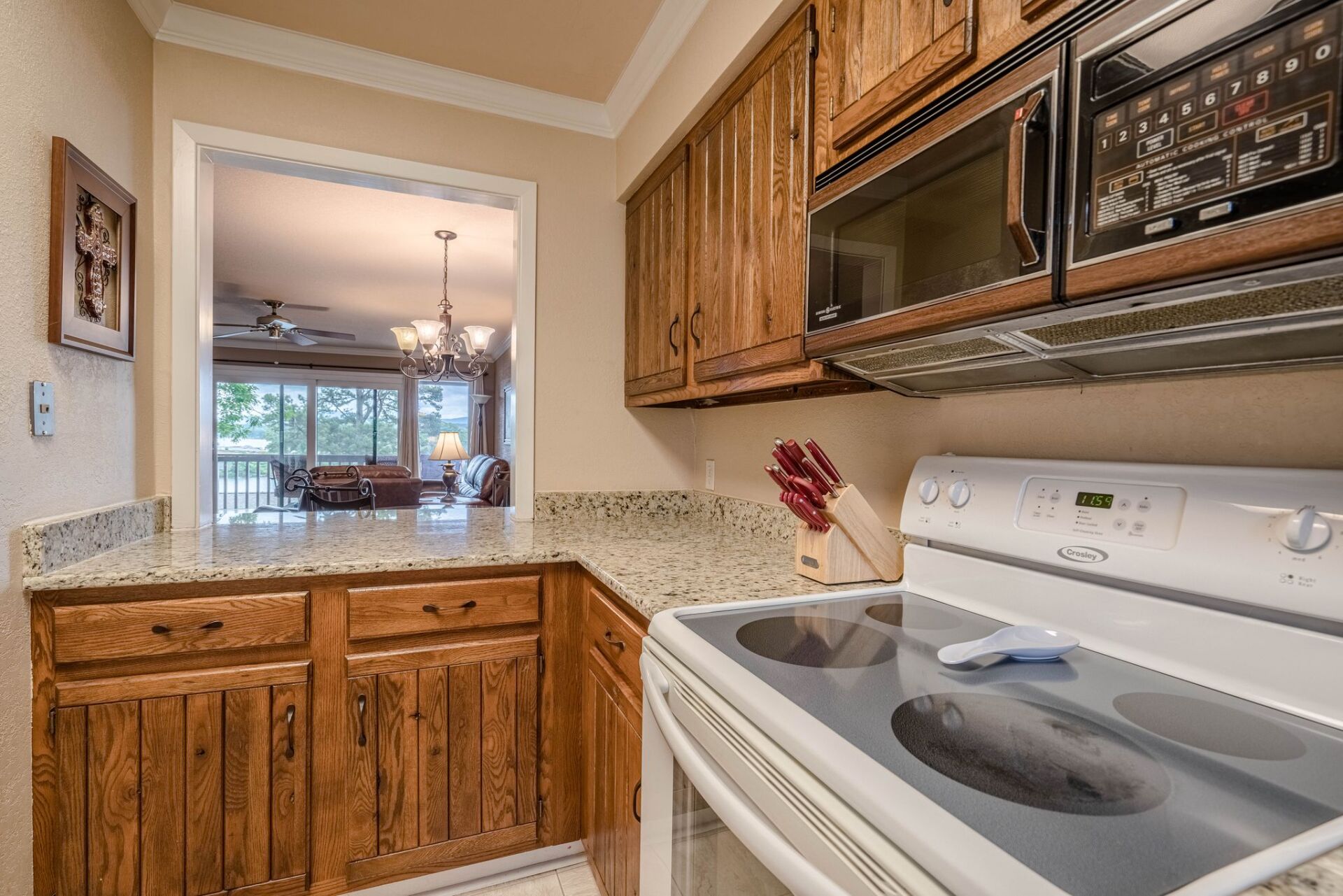 A kitchen with a stove , microwave , refrigerator and wooden cabinets.