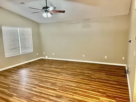 An empty living room with hardwood floors and a ceiling fan.