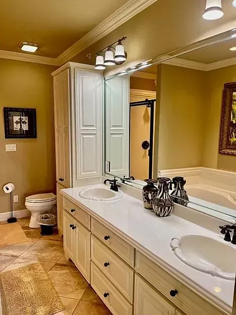 A bathroom with two sinks , a toilet , and a large mirror.
