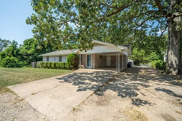 A house with a driveway and a tree in front of it.