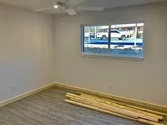 An empty room with a window and a ceiling fan.