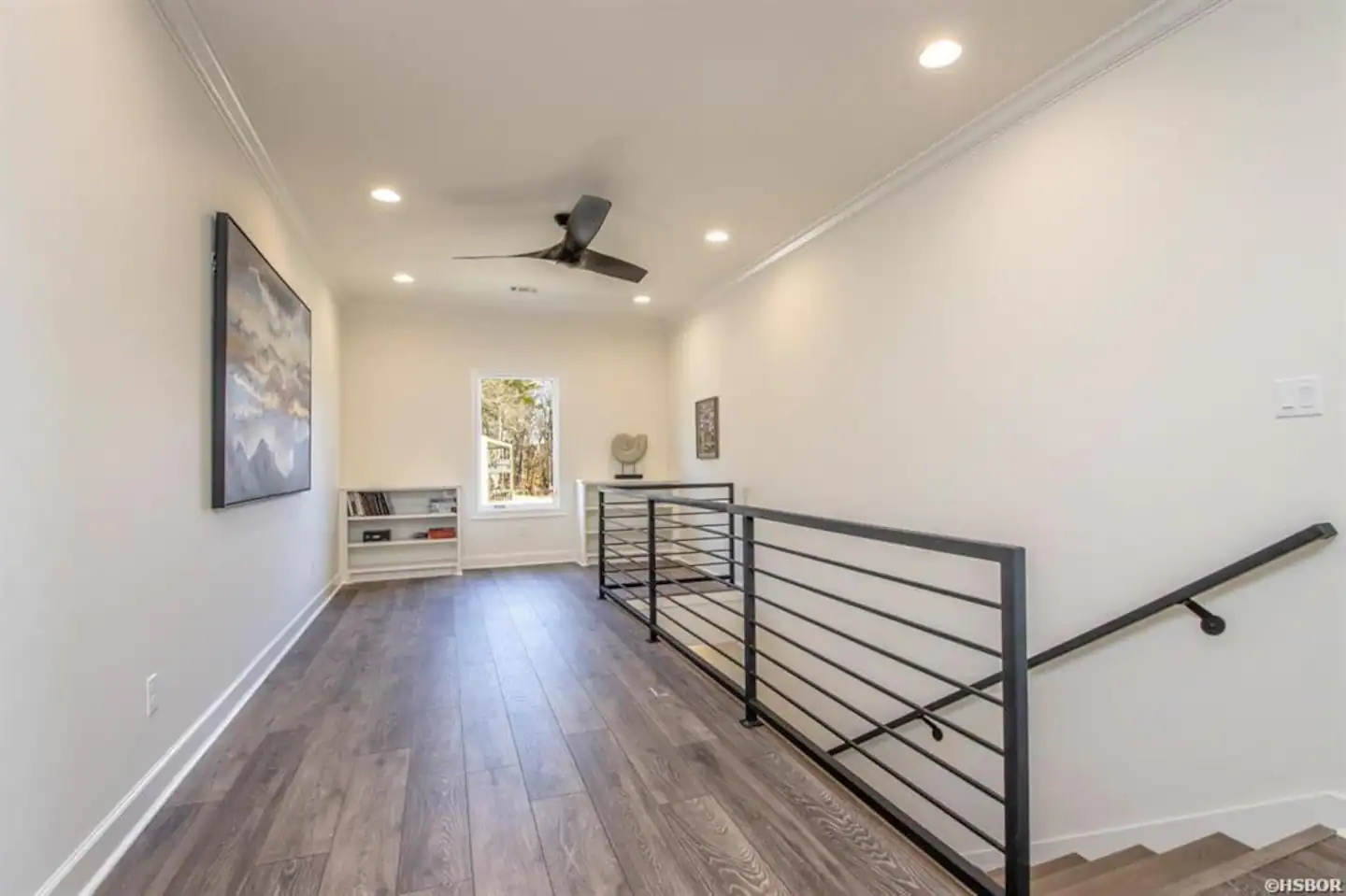 A hallway with stairs and a ceiling fan in a house.