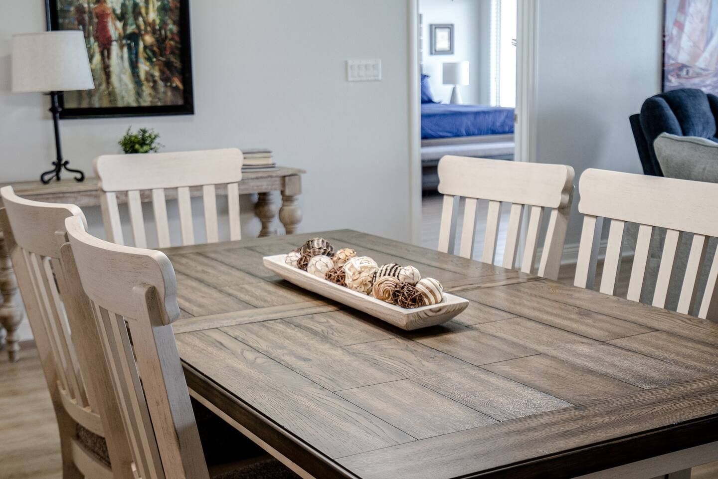 A wooden dining table with white chairs and a tray on it.
