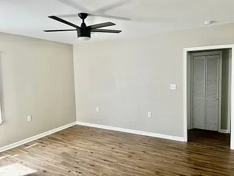 An empty living room with hardwood floors and a ceiling fan.
