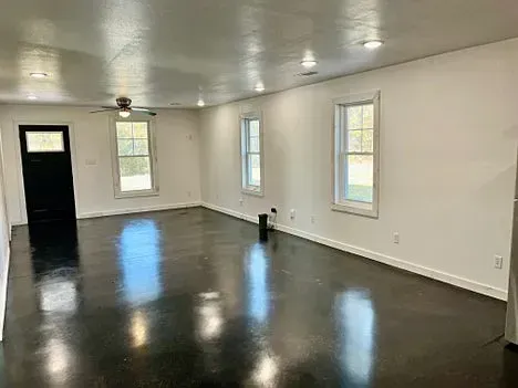 A large empty room with a black floor and white walls.