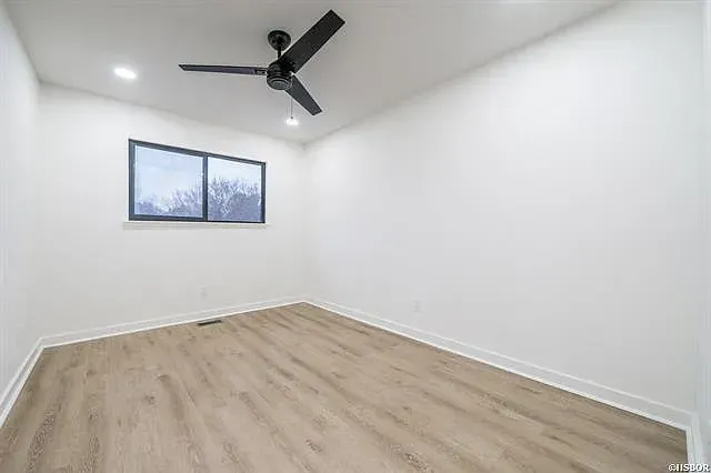 An empty bedroom with a ceiling fan and a window.