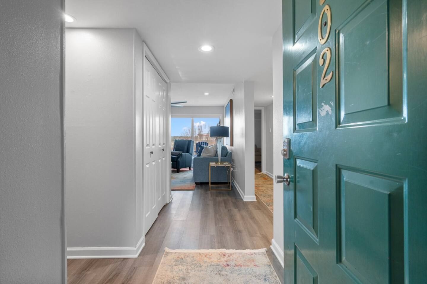 A blue door is open in a hallway leading to a living room.