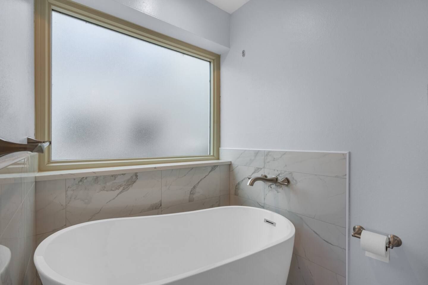 A bathroom with a bathtub and a window.