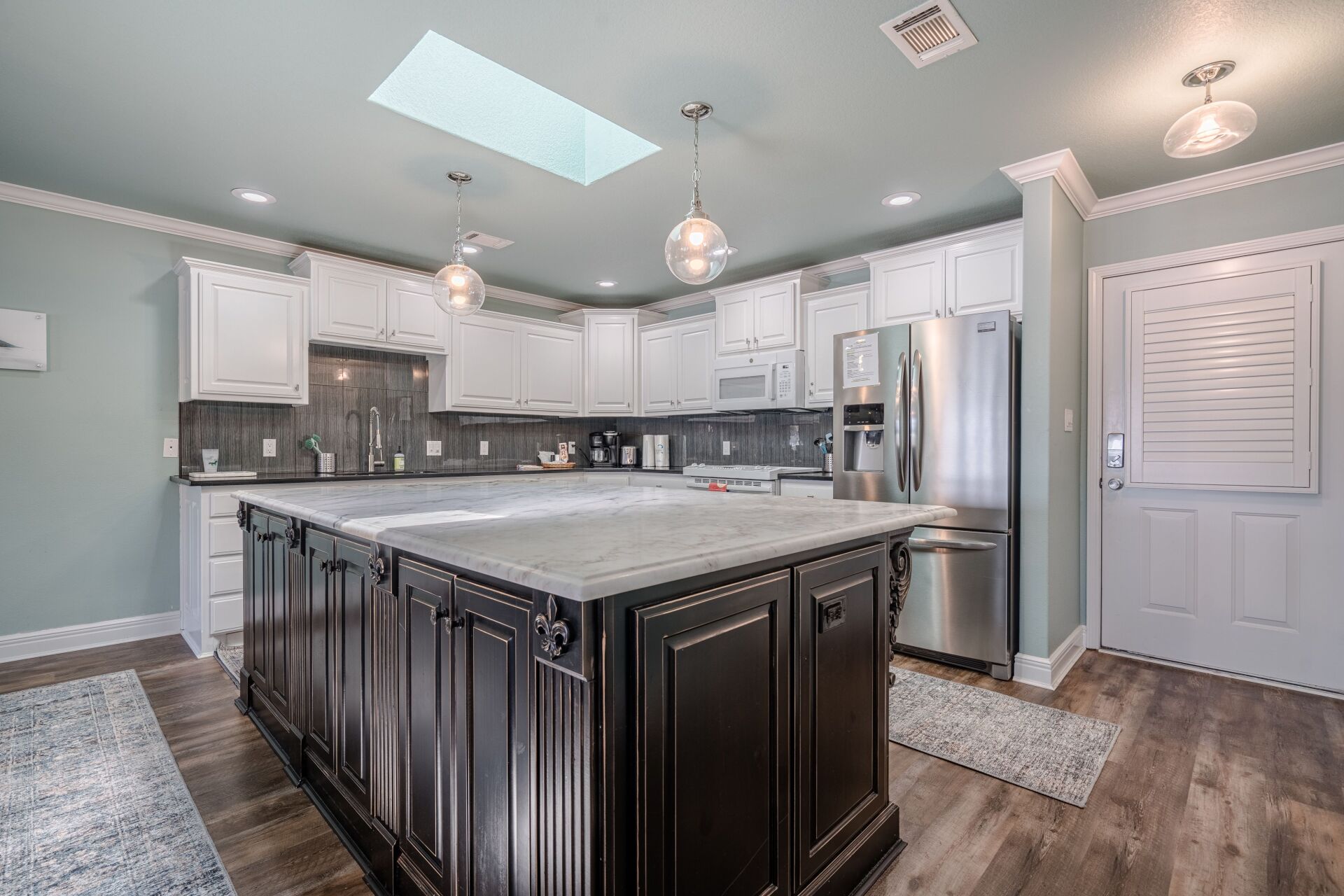 A kitchen with stainless steel appliances and a large island in the middle.