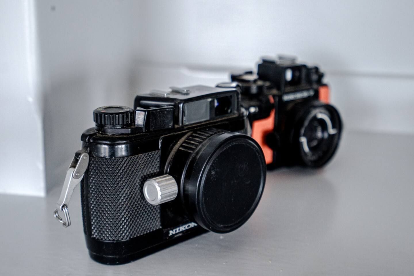 Two old cameras are sitting next to each other on a table.