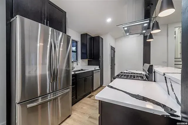 A kitchen with stainless steel appliances and black cabinets.