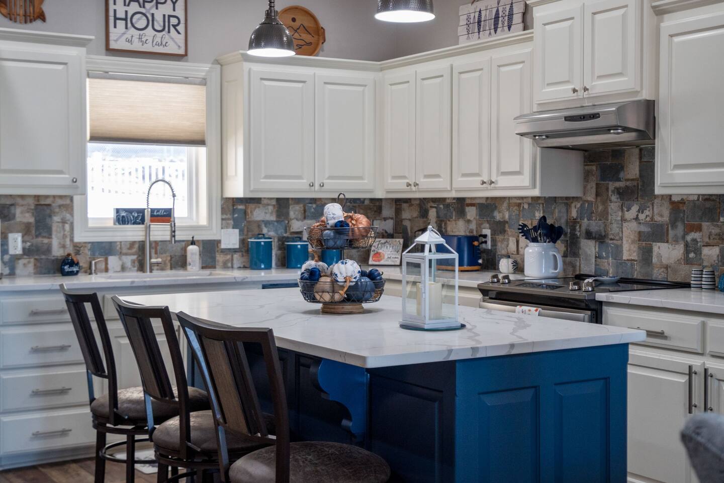 A kitchen with white cabinets and a blue island.