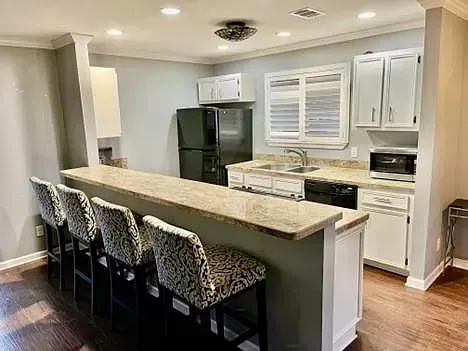 A kitchen with a refrigerator , sink , microwave and bar stools.