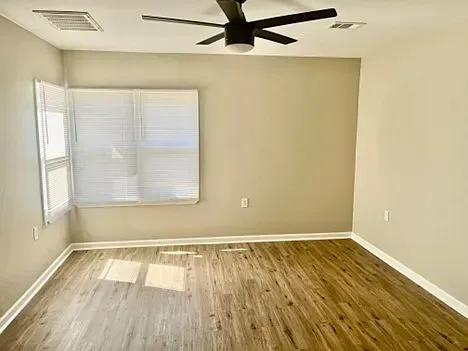 An empty room with a ceiling fan and a window.