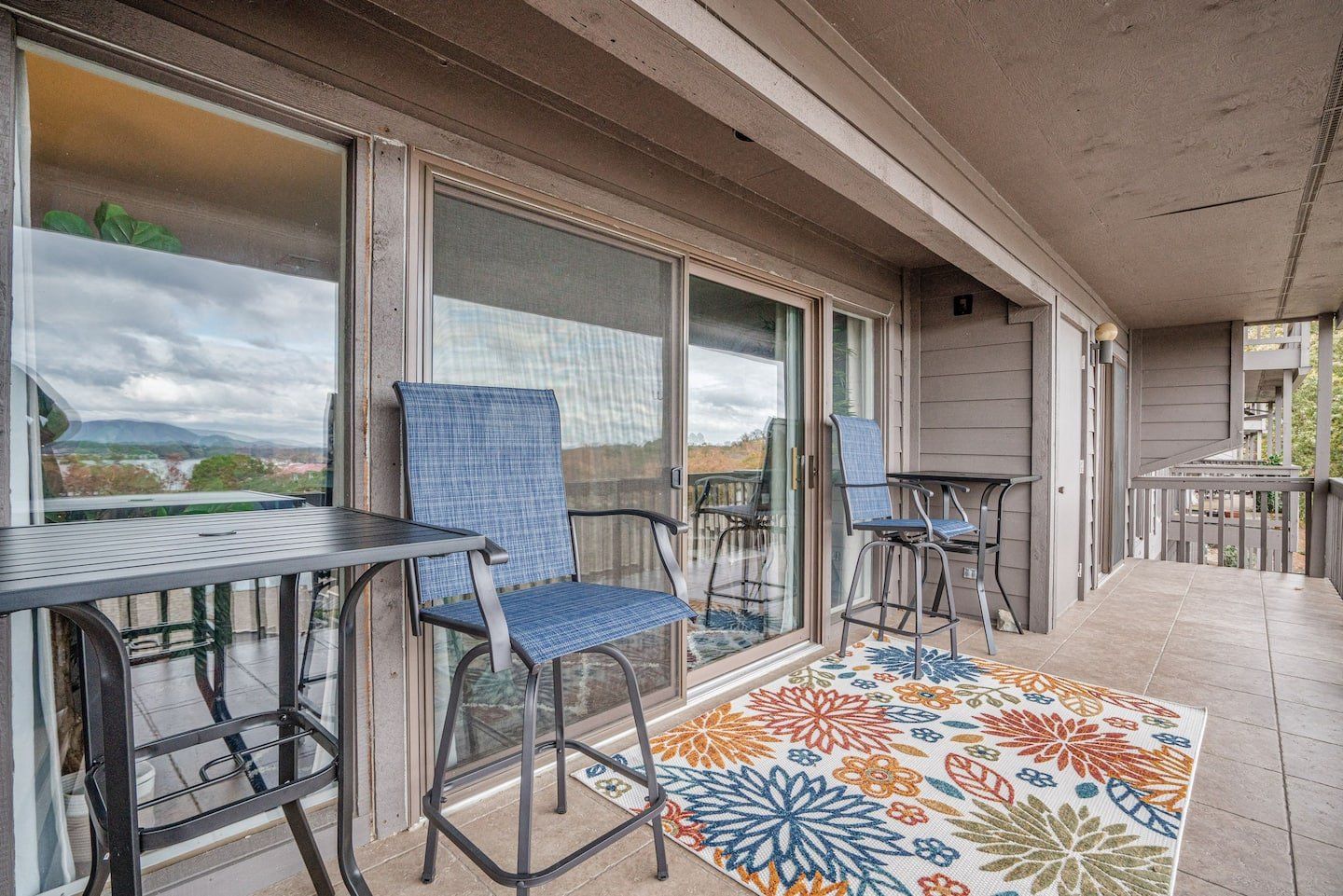 A balcony with a table and chairs and a rug.