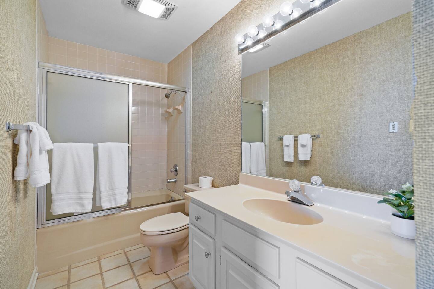 A bathroom with a sink , toilet , shower and mirror.