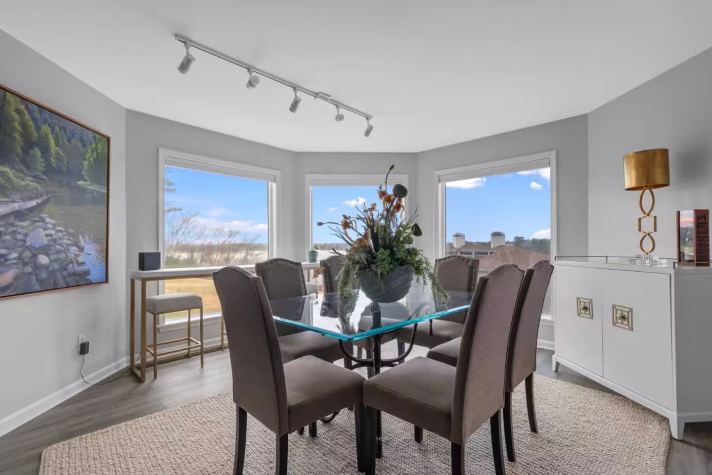 A dining room with a glass table and chairs and a large window.
