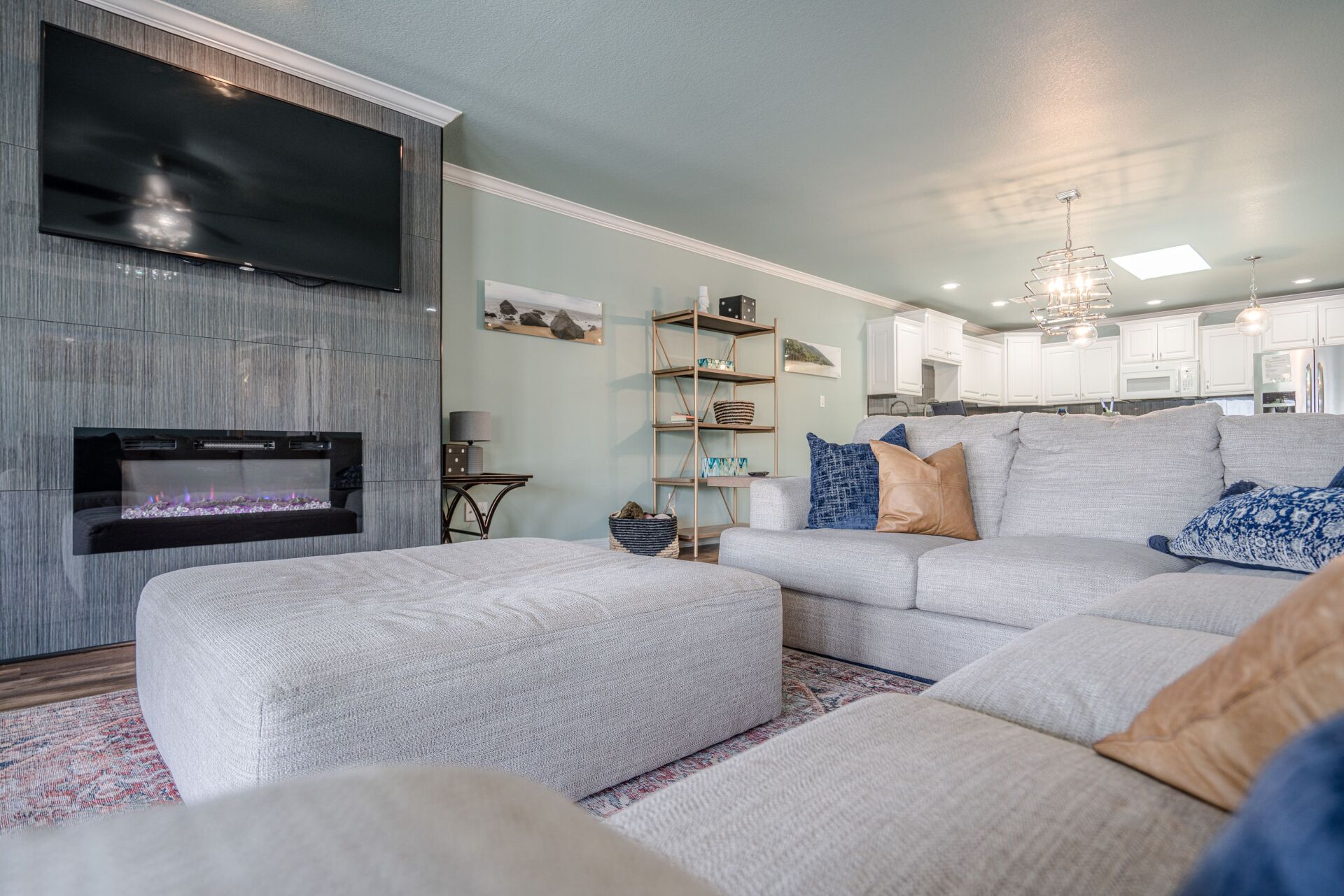 A living room with a couch , ottoman , fireplace and television.