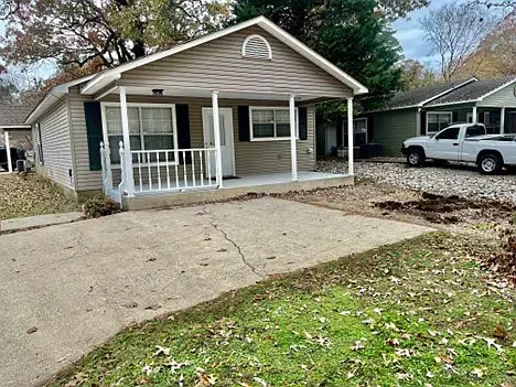 A small house with a porch and a truck parked in front of it.