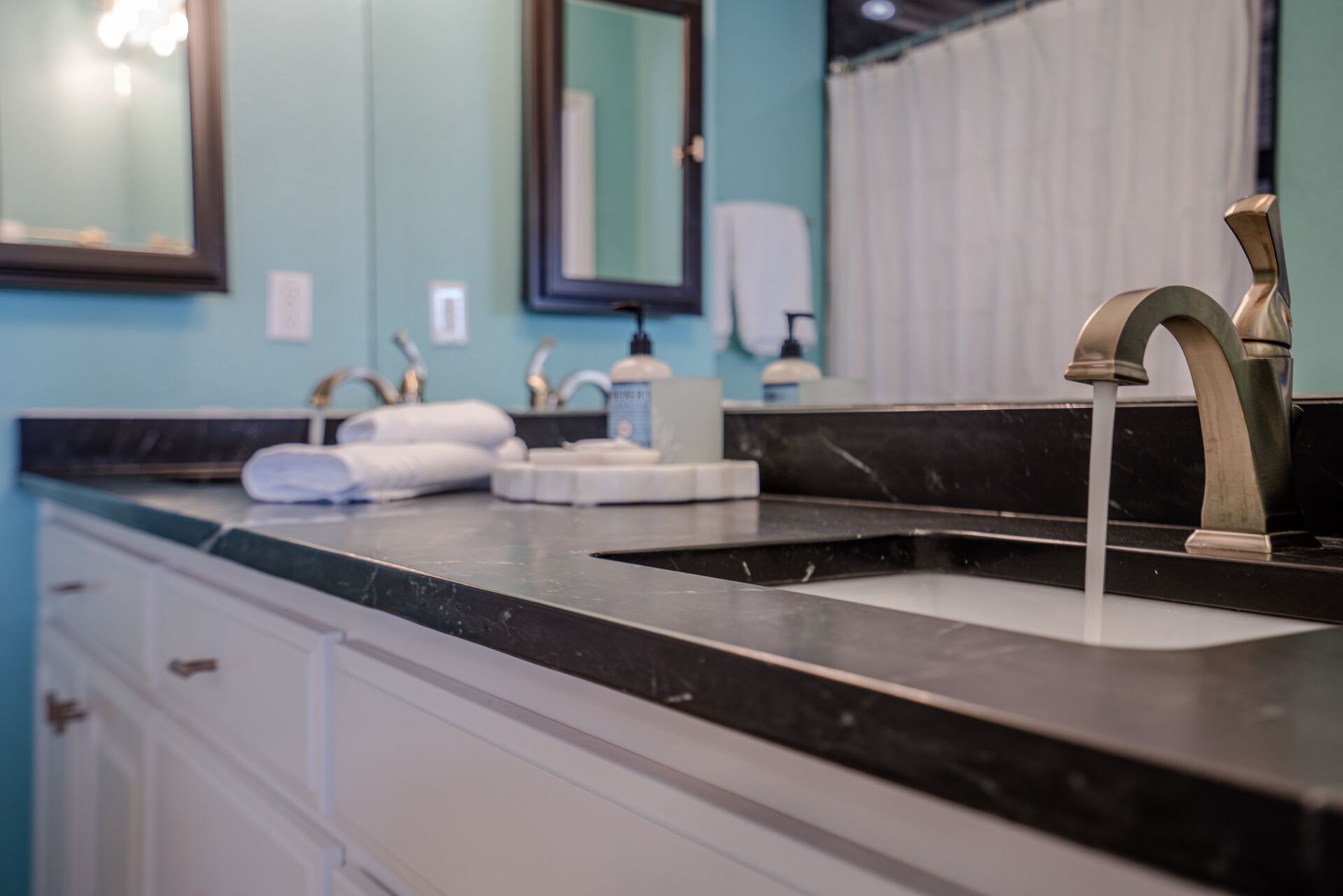 A bathroom with two sinks and a faucet running water.