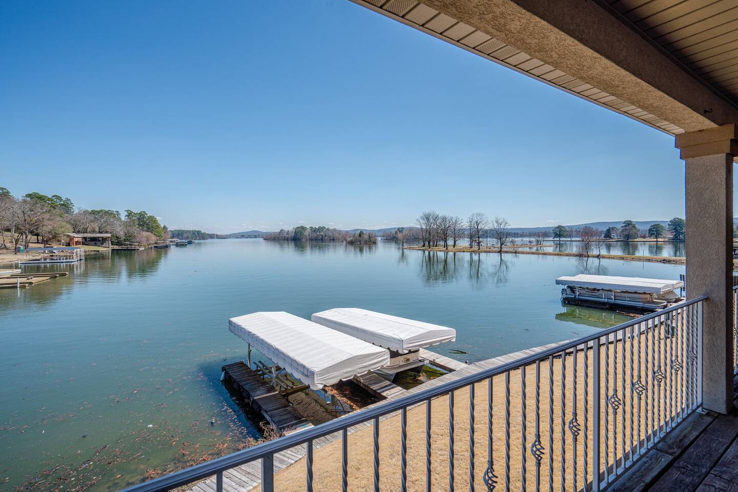 A view of a lake from a balcony with a railing.