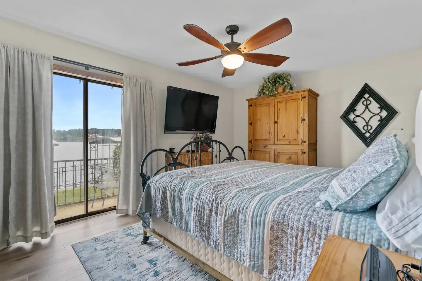 A bedroom with a large bed , ceiling fan , television and sliding glass doors.