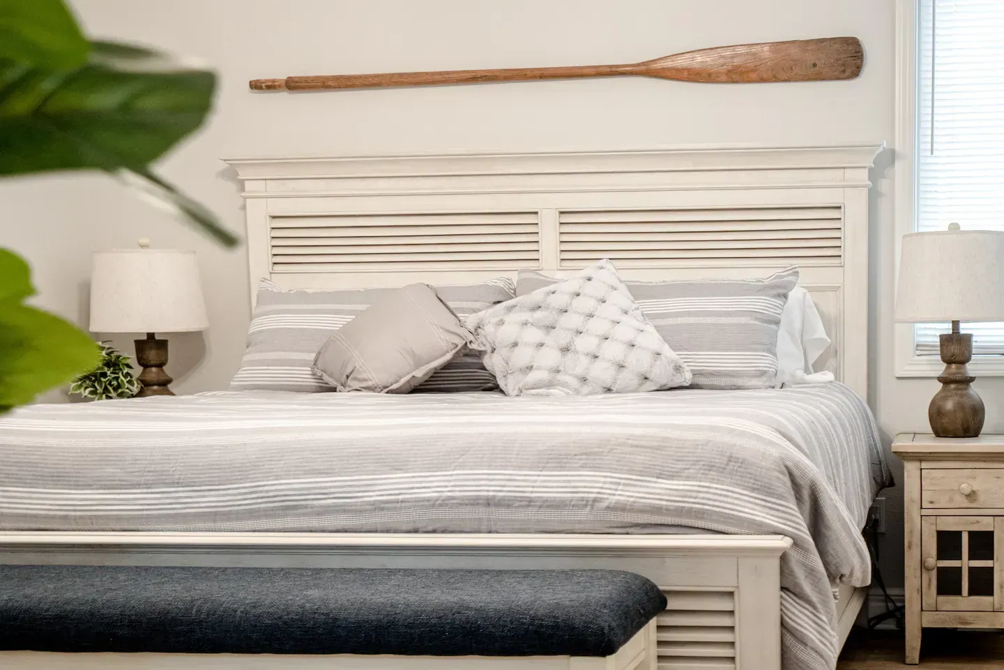 A bedroom with a bed , nightstand , lamp and oar on the wall.
