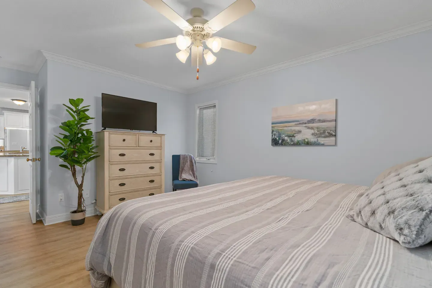 A bedroom with a bed , dresser , television and ceiling fan.