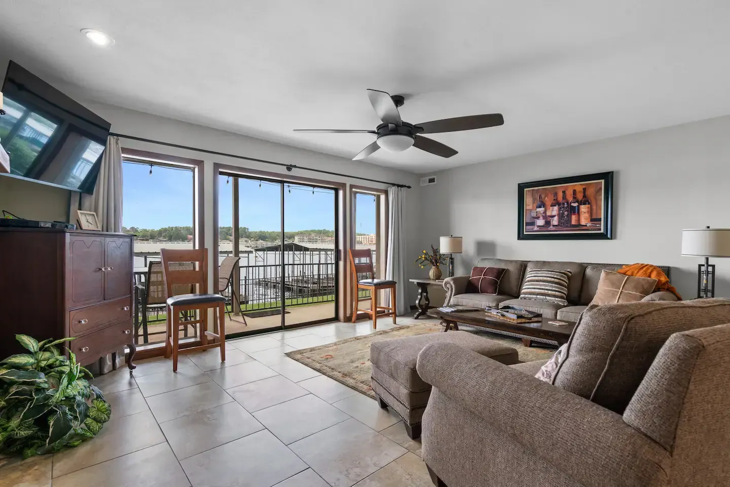 A living room with a couch , chairs , a television and a ceiling fan.