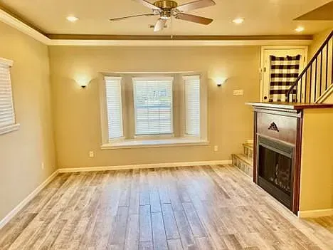 An empty living room with a fireplace and a ceiling fan.